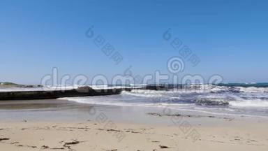 在阳光明媚的多风天气里，强烈的海浪拍打着码头和沙滩。 塞浦路斯海滩暴风雨天气